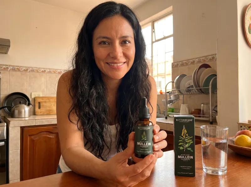 Mujer colombiana en la cocina de su casa, en la mañana, con el frasco de gotas Better Lungs