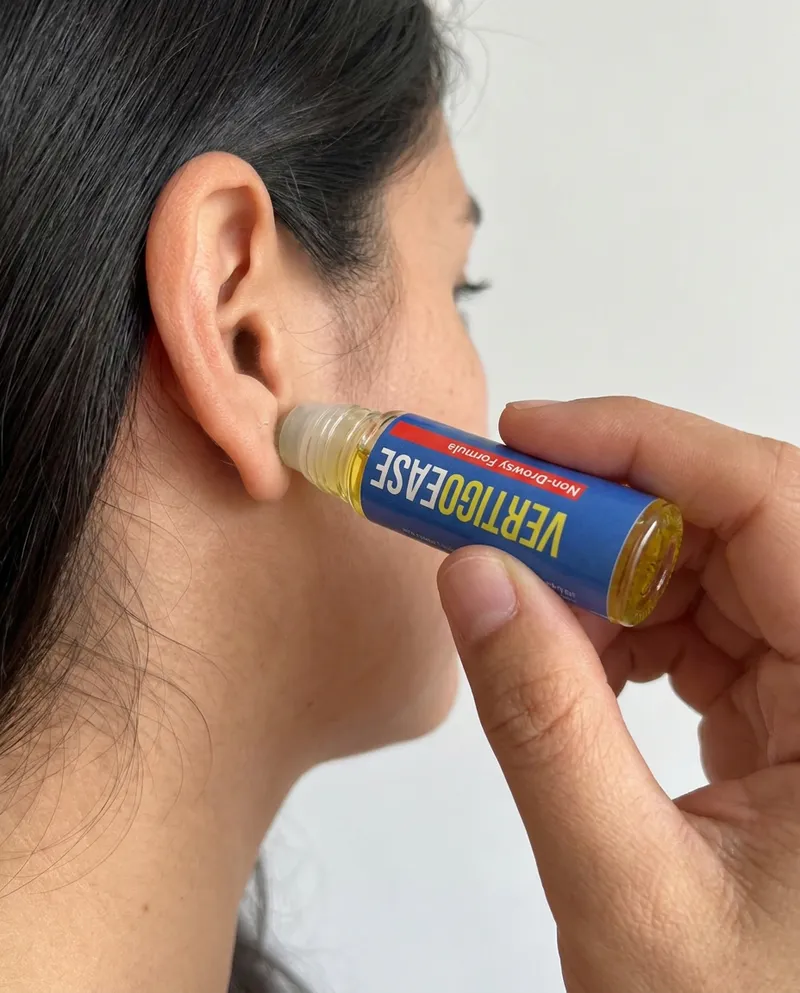 Mano pasando el roll-on Vertigo Ease detrás de la oreja